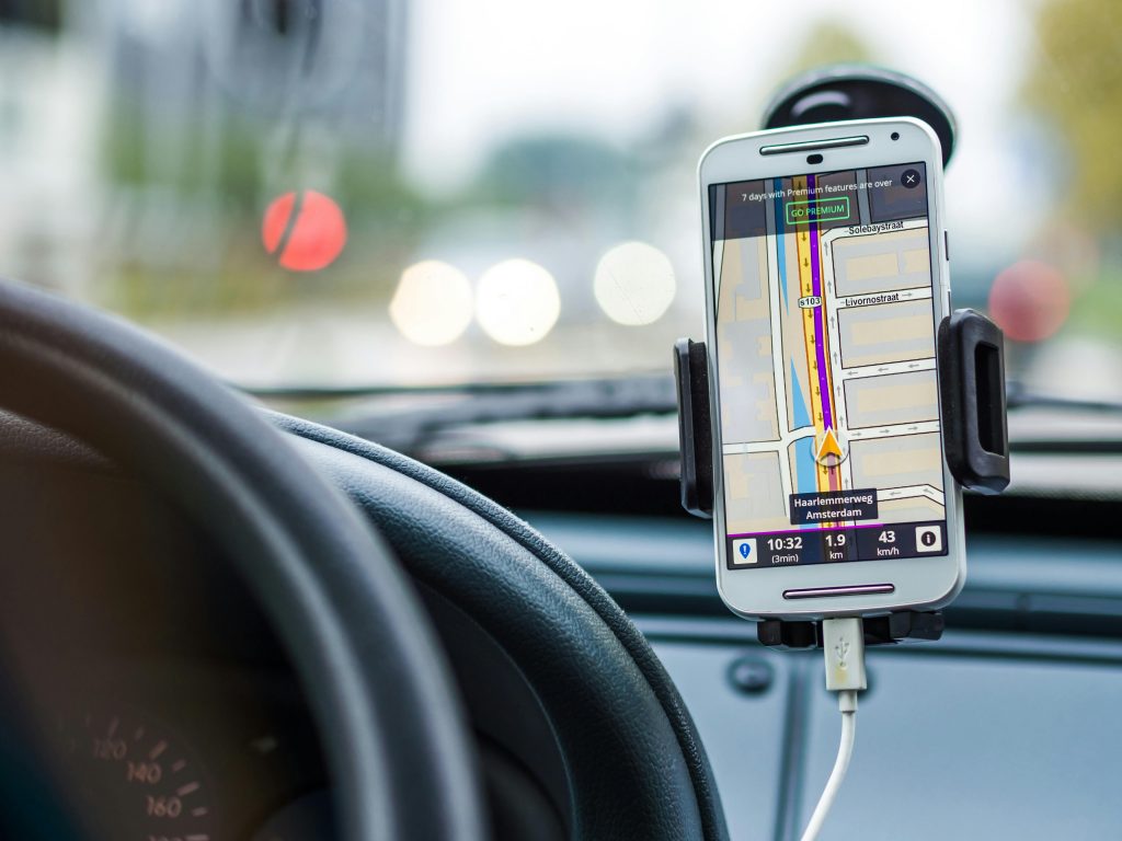 Stock photo of a phone mounted on the dash of a car while driving with navigation
